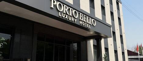 A modern building with the sign 'Porto Bello Luxury Hotel' indicating a hotel establishment.