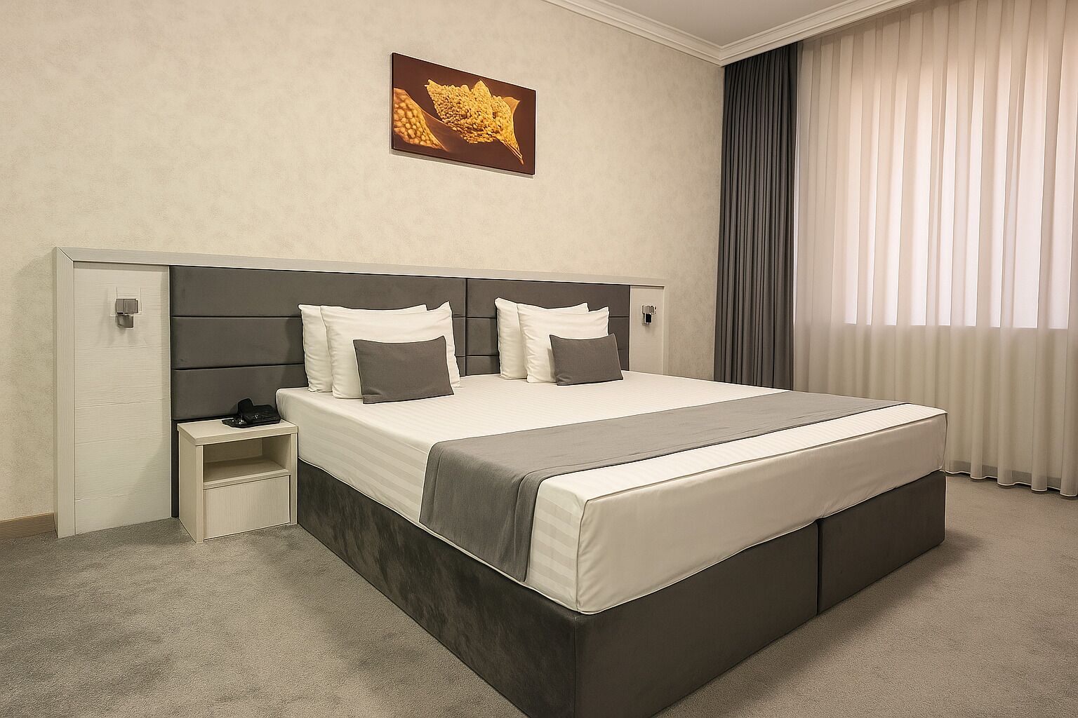 Ein Hotelzimmer mit einem großen Bett, einem Nachttisch, einem Wandbild und einem Fenster mit Vorhängen.