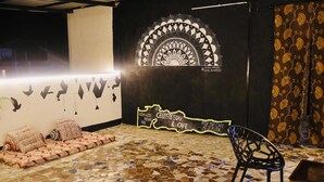 A room with a mosaic floor, a black and white wall art, a signboard, and a black chair. - CELESTE VILLA (Candolim)