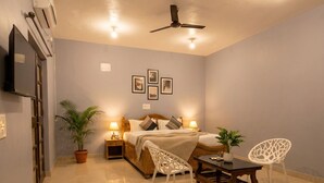 A bedroom with a bed, bedside tables, a ceiling fan, and wall-mounted lights. - CELESTE VILLA (Candolim)