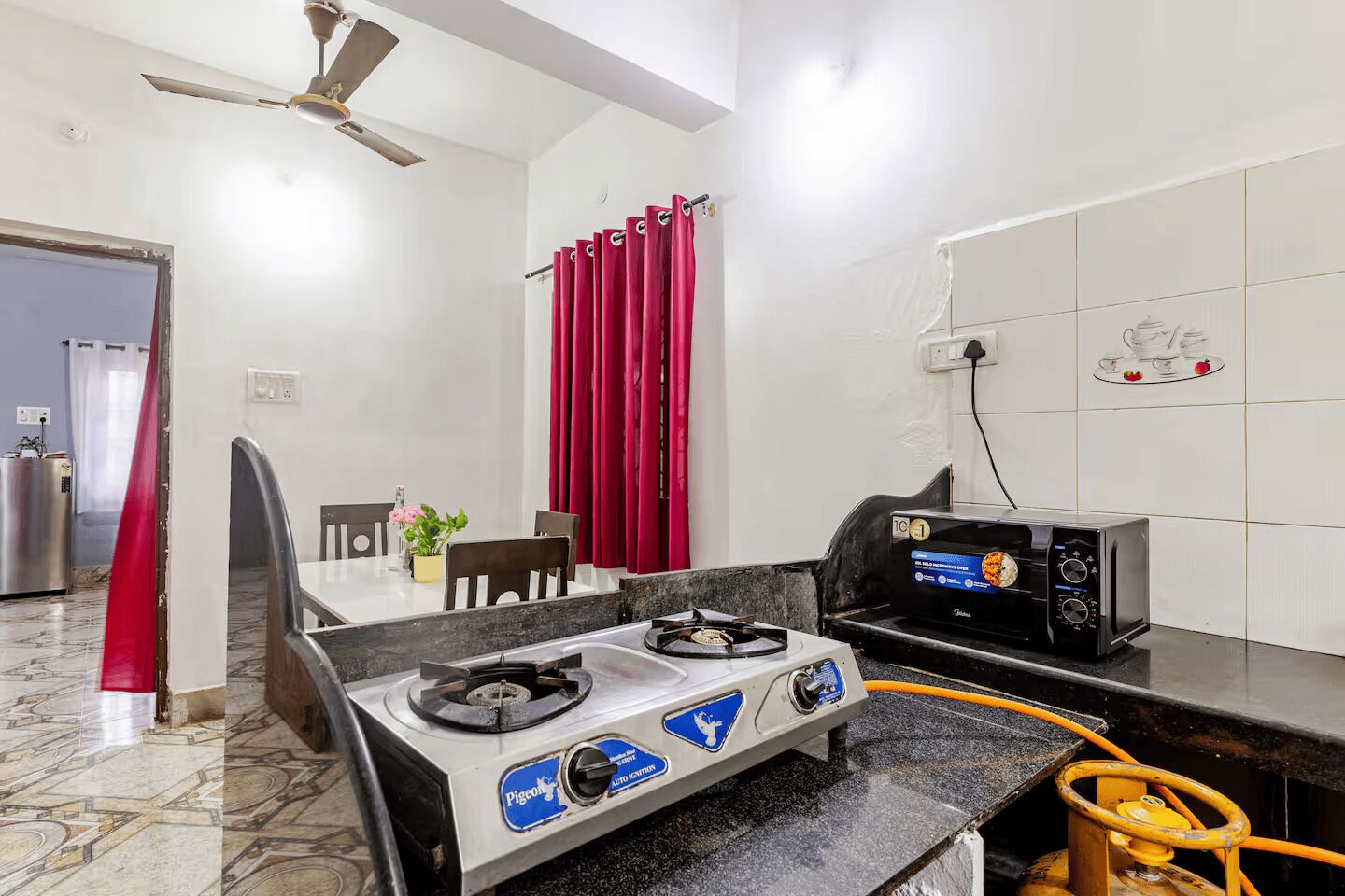 A kitchen with a gas stove, a microwave, and a dining table with chairs.