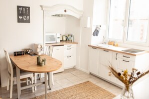 Une cuisine avec une table en bois, des placards blancs, un four à micro-ondes et une fenêtre donnant sur un beau paysage.