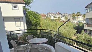 En balkon med et bord og stole, udsigt til kvarteret og et gelænder.