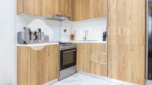A modern kitchen with wooden cabinets, a built-in oven, and a stainless steel range hood. - Bloomfields Fantastic 1Br Maryah (Abu Dhabi)