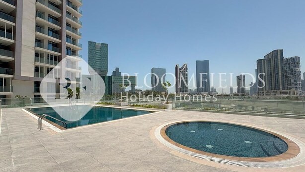 A modern residential building with a rooftop pool area, featuring a large rectangular pool and a smaller circular pool, set against a city skyline. - Bloomfields Fantastic 1Br Maryah (Abu Dhabi)