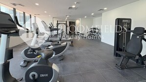 A gym with treadmills, elliptical machines, and weightlifting equipment. - Bloomfields Fantastic 1Br Maryah (Abu Dhabi)