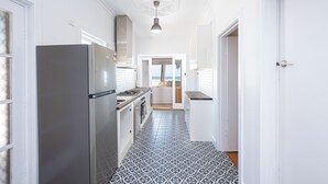 Een smalle keuken met een patroon vloer, een koelkast en een hanglamp.