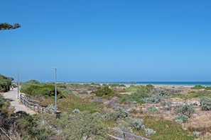 A coastal walkway with a wooden fence, leading to a pier extending into the sea. - The Largs Lookout - Modern Apartment (Largs North)