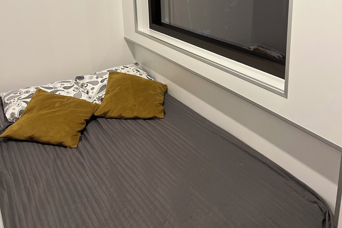A bedroom with a bed, a window, and an air conditioning unit.