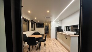 A modern kitchen with a dining area, wooden flooring, and built-in appliances.