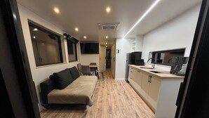A compact, modern room with a sofa, a small dining table, and a kitchenette.