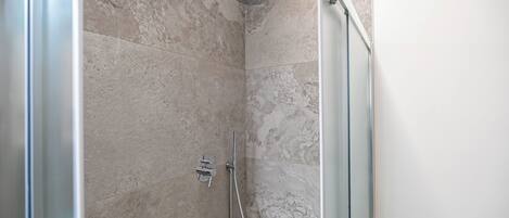 A modern shower with a handheld showerhead and a wall-mounted faucet.