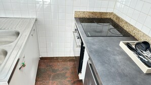 Keittiössä on valkoisilla laatoilla päällystetyt seinät, graniittitaso ja ruostumattomasta teräksestä valmistettu pesuallas.