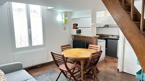 Eine kleine Küche mit Esstisch, Stühlen, einer Mikrowelle und einem Kühlschrank.