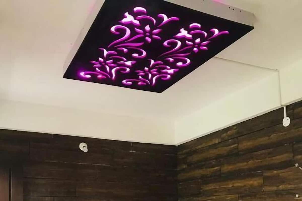 A bedroom with a bed, a red throw blanket, and a ceiling light fixture.