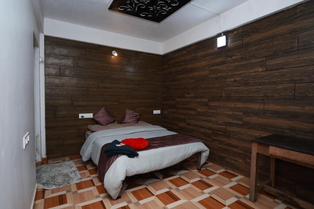 Une chambre avec un mur en bois, un lit avec des oreillers, un tapis et une petite table.