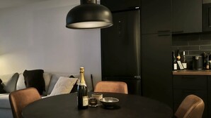 Moderni olohuone, jossa on sohva, ruokapöytä ja samppanjapullo sekä keittiöalue, jossa on viinipulloja.
