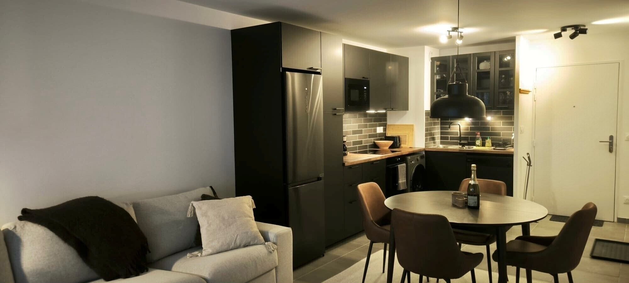 A modern kitchen with a built-in oven, a refrigerator, and a dining area with a table and chairs.