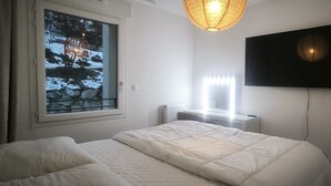 Makuuhuone, jossa on sänky, ikkuna, josta avautuu näkymä kallioille, patteri ja seinälle asennettu televisio.