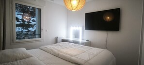 Ein Schlafzimmer mit einem Bett, einem Fenster mit Blick auf Felsen, einem Heizkörper und einem an der Wand befestigten Fernseher.