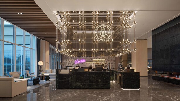 Eine moderne Lobby mit einer Rezeption, einer Sitzgelegenheit und großen Fenstern.