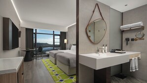 Ein modernes Hotelzimmer mit einem großen Bett, einem Badezimmer mit einem großen Spiegel, einem Waschbecken und Blick auf die Berge.