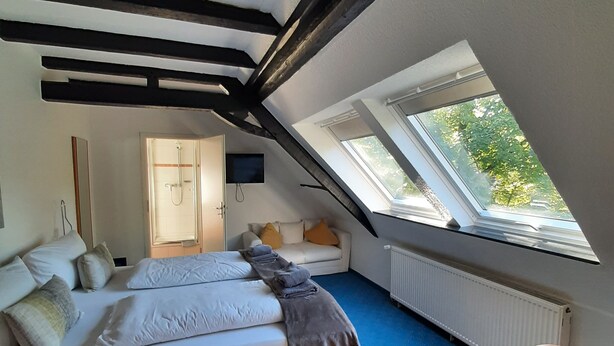 A bedroom with a bed, a chair, a window, and a radiator.