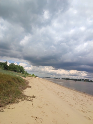 Ein sandiger Strand mit Fußabdrücken und einem Rasenbereich.