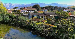 A residential area with houses, a pond, and mountains in the background. - Villa Mariapia 6P, by VILLASRETREATS Beach House, just a few steps from the ocean (Massa)