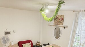 A compact living space with a red sofa, a dining table, and a small kitchen area. - Charming Studio Apartment in Lucca in the Historic Center - BanStay (Lucca)