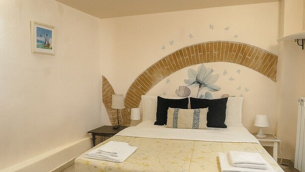 A bedroom with a bed, a nightstand, a lamp, and a picture on the wall. - Charming Studio Apartment in Lucca in the Historic Center - BanStay (Lucca)