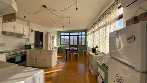 A kitchen with white cabinets, a central island, a dining table with chairs, and a refrigerator.