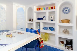 Una stanza con un tavolo bianco, sedie blu e scaffali con oggetti decorativi.