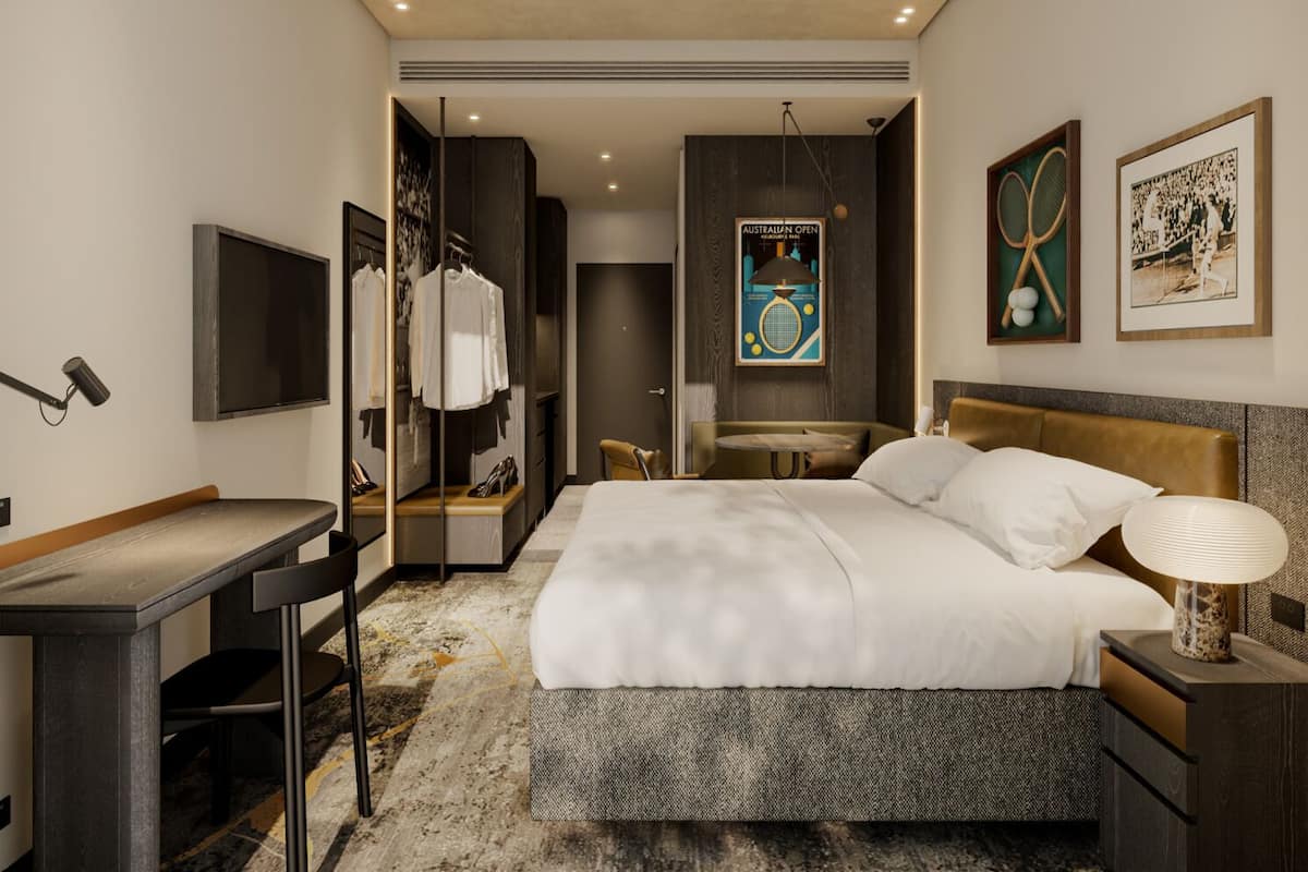 A hotel room with a bed, desk, chair, and a mirror.
