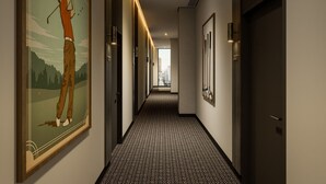 A hallway with patterned carpet, framed artwork, and doors leading to rooms. - Veriu Richmond (Richmond)