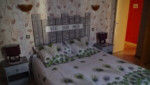 A bedroom with a bed, nightstands, and a wall with a floral pattern and a sign that reads "VUE SUR MER". - Au Calme 4 star house 2 bedrooms large swimming pool 6x12 m sea and town 1,5 km (Saint-Pierre-d'Oléron)