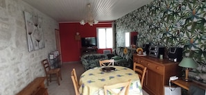 Una habitación con una mesa de comedor, sillas, televisor, sofá y una pared con diseño.