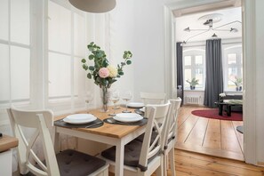 Ein Essbereich mit einem Holztisch, gedeckt für vier Personen, weißen Stühlen und einem Blumenstrauß.