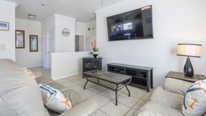 Ein Wohnzimmer mit einer Couch, einem Couchtisch, einem Fernseher und einem Kamin.