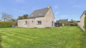 A single-story house with a sloped roof, a small front porch, and a well-maintained lawn. - Beach 200m away, house for 6 with garden (Guissény)