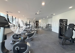 Ein Fitnessstudio mit Laufbändern, Crosstrainern und Gewichten.