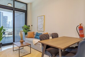 Ein modernes Wohnzimmer mit einer Couch, Sesseln, einem Couchtisch und einem Feuerlöscher an der Wand.