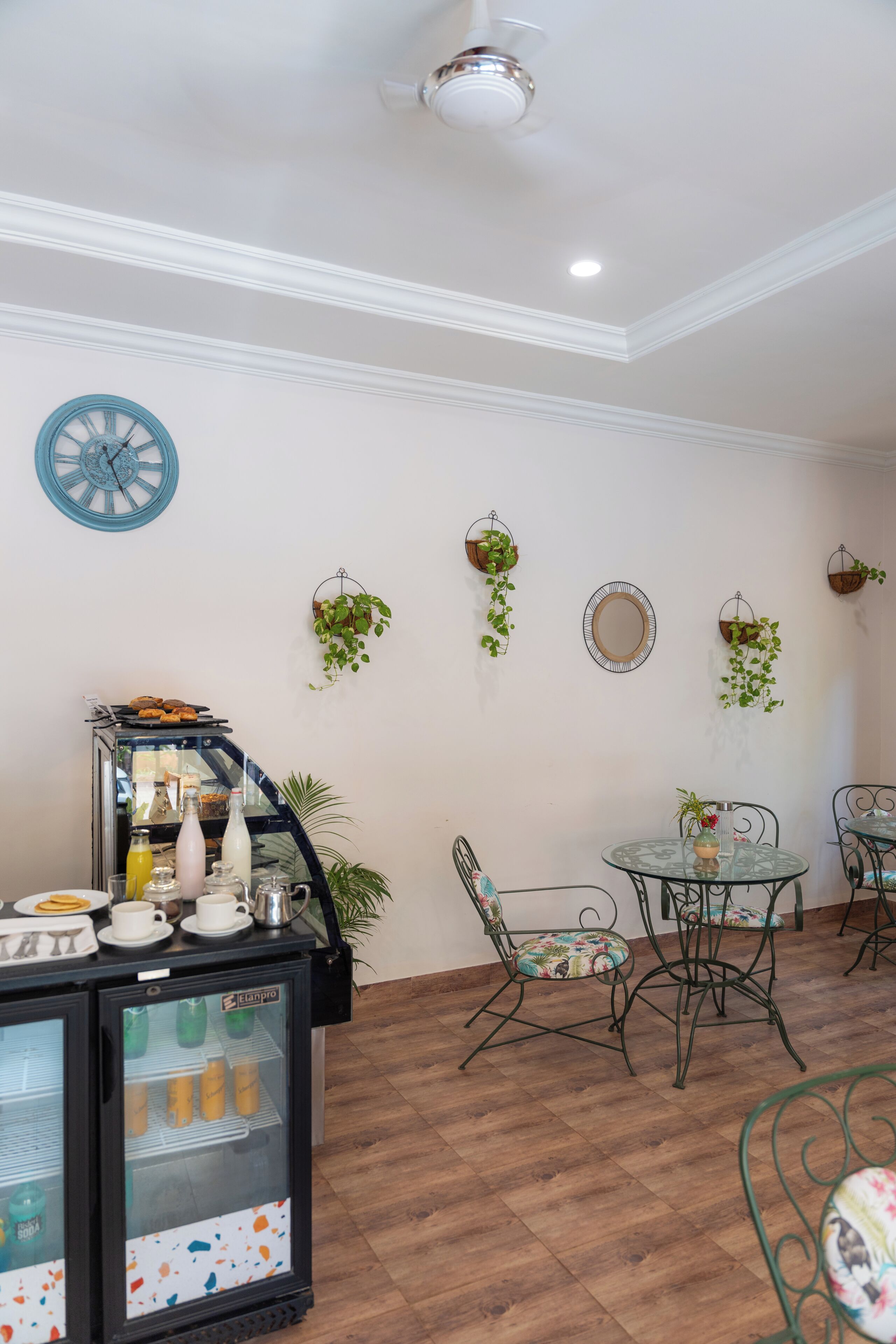 A cafe area with a coffee machine, seating, and decorative plants.