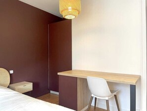 A bedroom with a bed, a desk, and a chair.