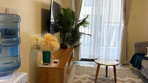 A living room with a sofa, a coffee table, a TV, a water dispenser, a potted plant, and a patterned rug. - Enjoyable 1-bedroom apartment perfect for a relaxing getaway (Nairobi)