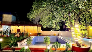 A well-lit outdoor area with a pool, potted plants, and a staircase leading to an upper level. - Devora Resort (Rishikesh)