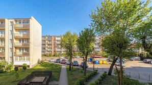 A residential building with multiple balconies, a parking area, and a small garden with trees and a pathway. - Comfortable Apartment in Gdansk | Balcony | Workspace (Gdańsk)