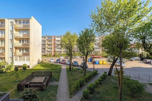 A residential building with multiple balconies, a parking area, and a small garden with trees and a pathway. - Comfortable Apartment in Gdansk | Balcony | Workspace (Gdańsk)