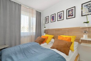 Een moderne slaapkamer met een bed, kussens, een nachtkastje en een bedtafel.