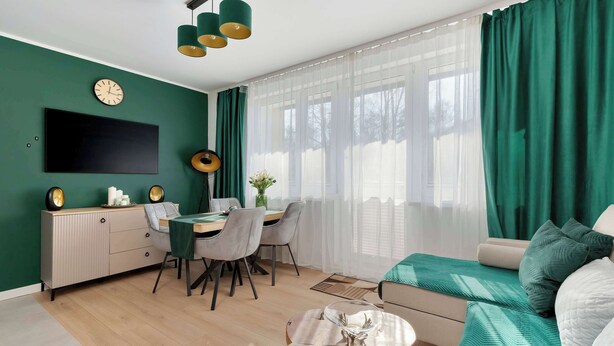 A modern living room with a sofa, a dining table, and a TV mounted on the wall. - Comfortable Apartment in Gdansk | Balcony | Workspace (Gdańsk)